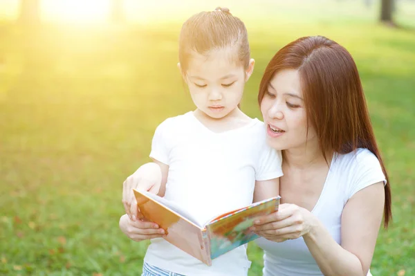 Mother and daughter reading outdoors. — Stock Photo, Image