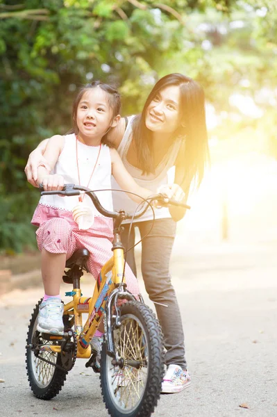 Kind leren om te fietsen met hulp van moeder buiten. — Stockfoto