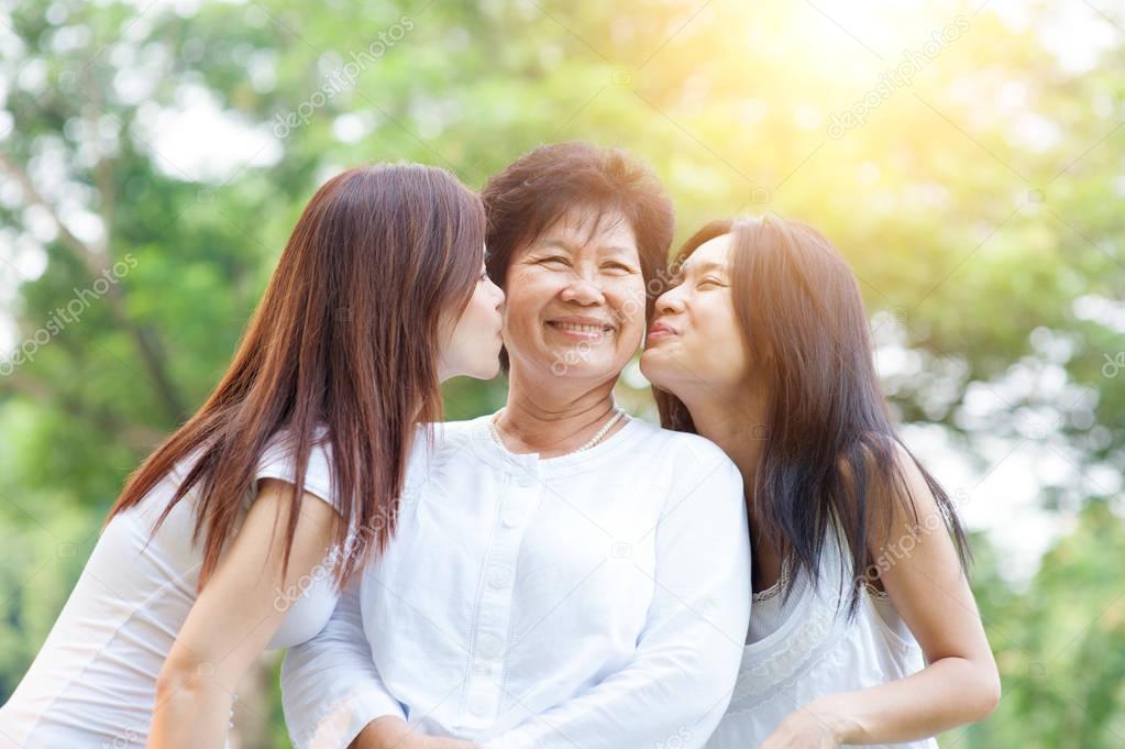 Daughters kissing elderly mother