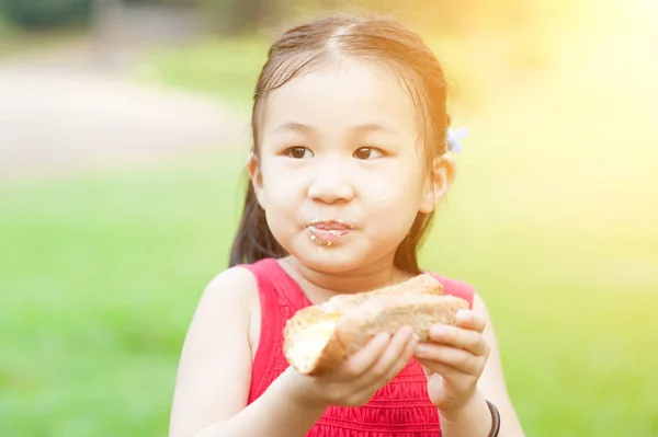 Asian child eating outdoors. — Stock Photo, Image