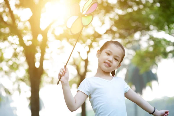 Asiatisches Kind spielt Windmühle im Freien. — Stockfoto