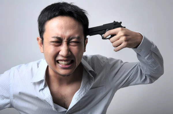 Hombre de negocios asiático apuntando con un arma a su cabeza —  Fotos de Stock
