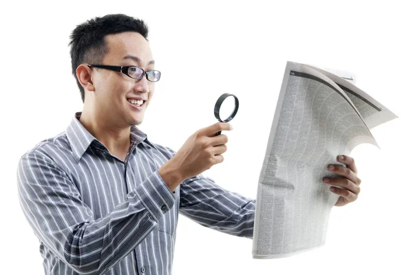 Hombre asiático leyendo periódico con lupa — Foto de Stock