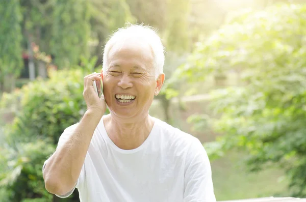 Aasialainen vanha mies puhelimessa — kuvapankkivalokuva