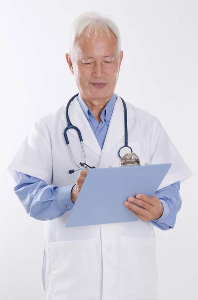 Old Asian medical doctor writing report — Stock Photo, Image