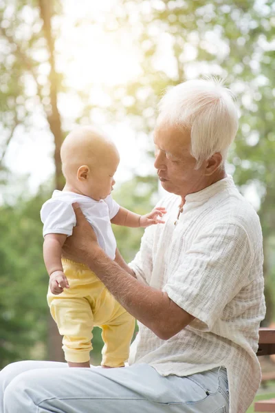 Дедушка держит внука на открытой скамейке . — стоковое фото
