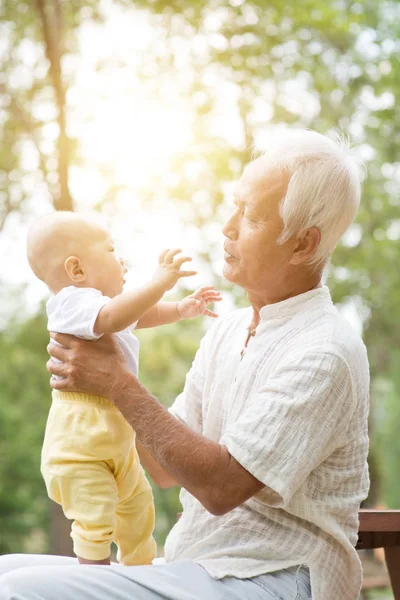 Avô brincando com o neto no banco ao ar livre . — Fotografia de Stock