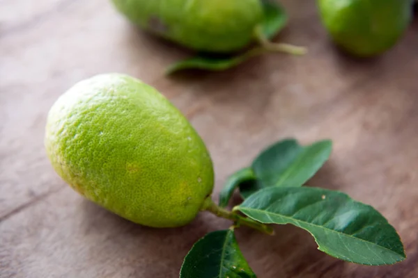 Biologische groene citroenen met bladeren — Stockfoto