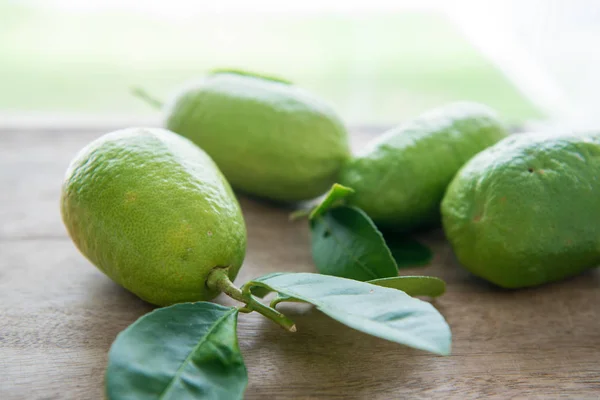 Biologische groene citroenen op houten achtergrond — Stockfoto