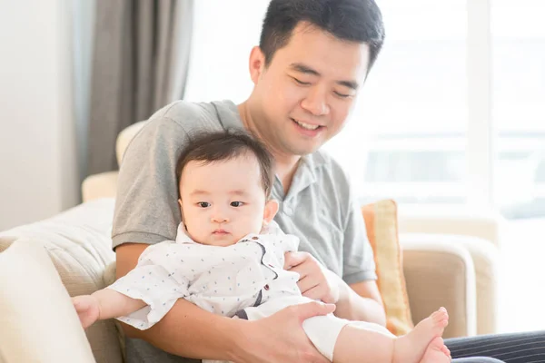 Father holding baby sitting on sofa. — Stock Photo, Image