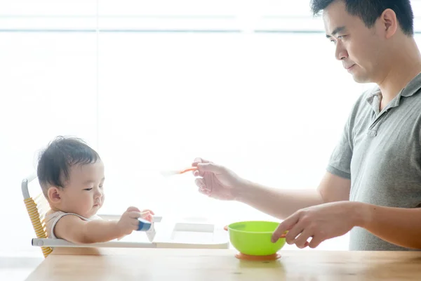 Father feeding baby solid food. — Stock Photo, Image