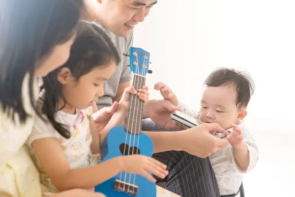 Семья играет на укулеле и губной гармошке дома — стоковое фото