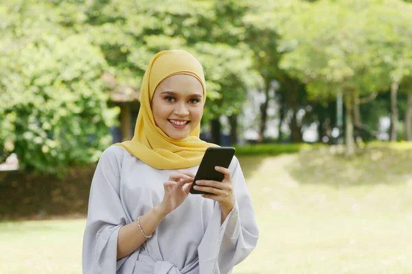 Πορτρέτο Του Χαρούμενου Μουσουλμάνου Κοριτσιού Χρησιμοποιώντας Smartphone Χαμογελώντας Εξωτερικούς Χώρους — Φωτογραφία Αρχείου