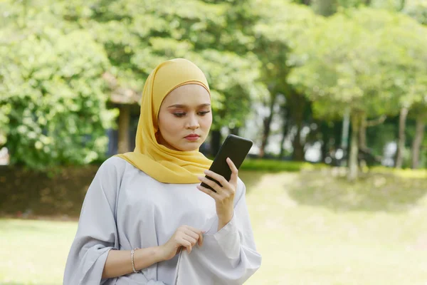 携帯電話を見ているイスラム教徒の女性 負の感情 フィッシング詐欺の概念 — ストック写真