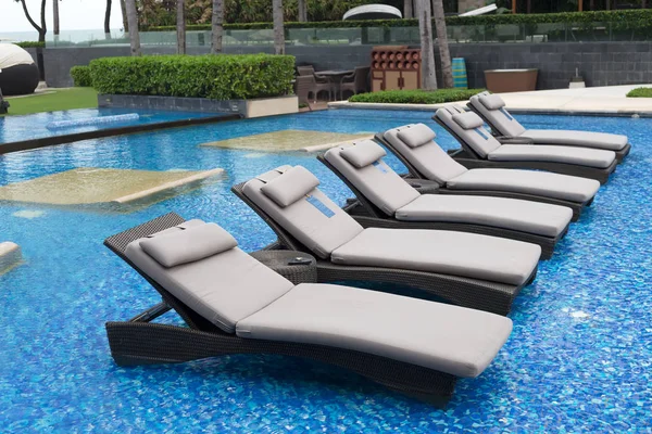 Ligstoelen met handdoeken op zwembad met blauw water — Stockfoto