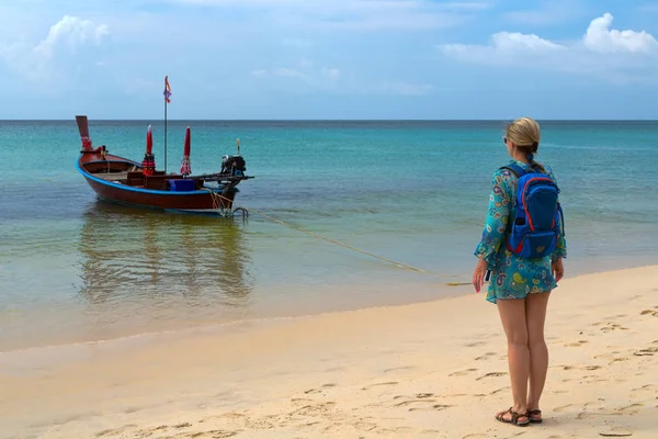 Дівчина з рюкзаком на пляжі, традиційні тайські човен — стокове фото