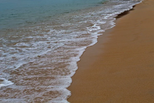 Sand på stranden och skummande vatten — Stockfoto