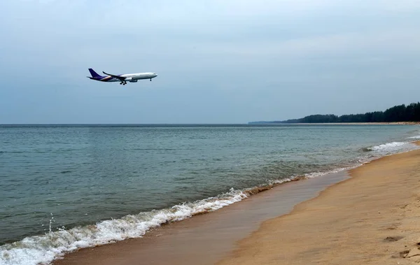 Airplane landing above beautiful beach and sea background — Stock Photo, Image