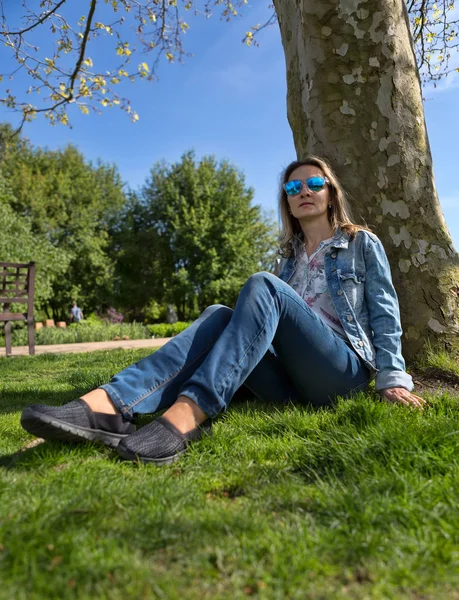 Mädchen im Park sitzt auf dem Boden neben einem Baum — Stockfoto