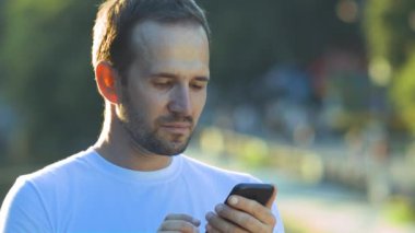 Adam caddedeki telefona bakıyor, yakın plan.