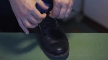 Erkek adam siyah deri ayakkabıları bağlar, yakın plan.