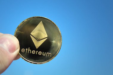 Holding Ethereum Sky.Crypto para birimine Ethereum, Eth, kripto bozuk para ver. Ethereum altın sikke mavi gökyüzü arka plan üzerinde makro çekim. Blockchain teknoloji, araştırma kavramı