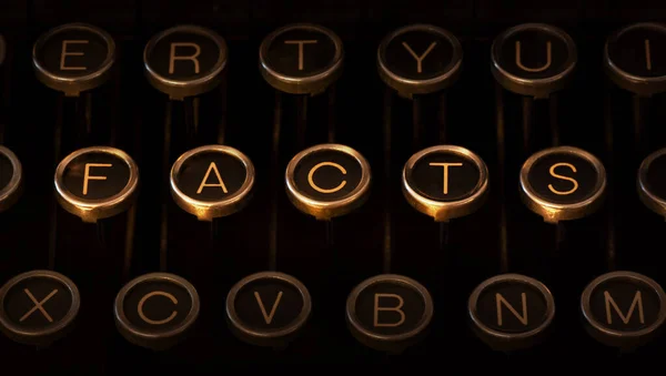 带有划痕铬键的老式打字机键盘的照片 在中间 闪亮明亮的键从 Facts 中形成 而其他键在低光中退缩 — 图库照片