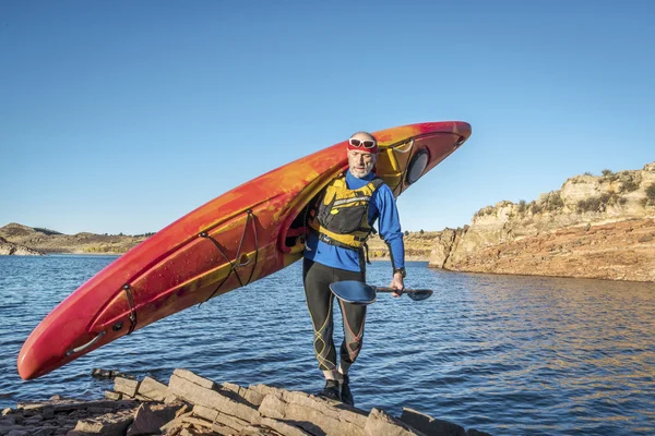 Carrying river kayak on lake shore — Stock Photo, Image