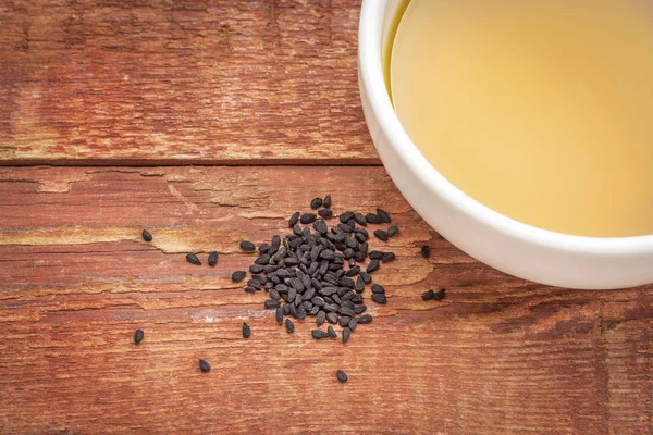 Black cumin seeds and oil — Stock Photo, Image