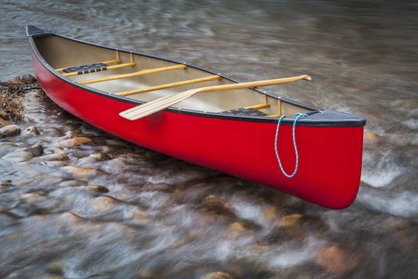 Canoa rossa su un fiume roccioso poco profondo — Foto Stock