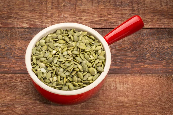 Pumpkin seeds in a stoneware cup — Stock Photo, Image