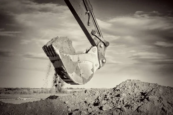 Excavator arm and scoop digging dirt at construction site — Stock Photo, Image