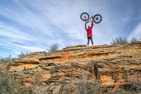Erkek binici şişman bisikletini kumtaşı uçurumdan kaldırma — Stok fotoğraf