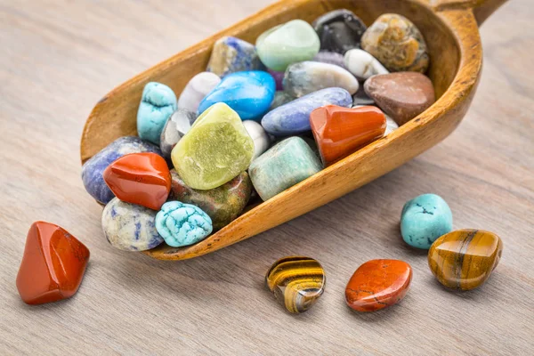 Polished, colorful gemstone in rustic wooden scoop — Stock Photo, Image