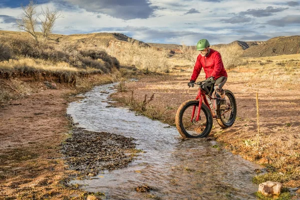 Riding a fat bike across a stream — Stock Photo, Image