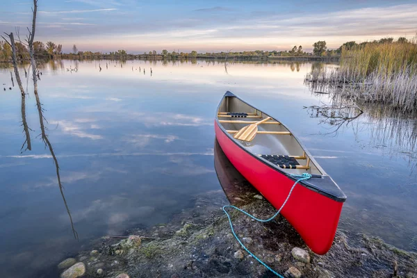 Красное каноэ на берегу озера — стоковое фото