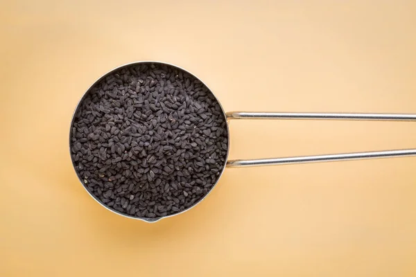 Black cumin seeds in a measuring scoop — Stock Photo, Image