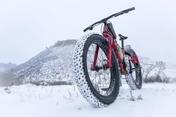 Vet mountainbike in een sneeuwstorm van sneeuw — Stockfoto