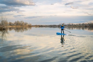Paddleboard sakin gölde kürek çekmeye ayağa