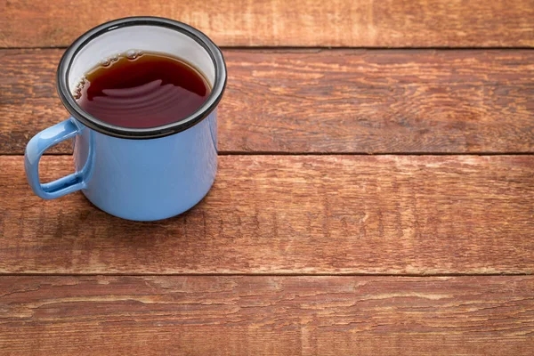 Metal cup of hot tea on a rustic picnic table — Stock Photo, Image