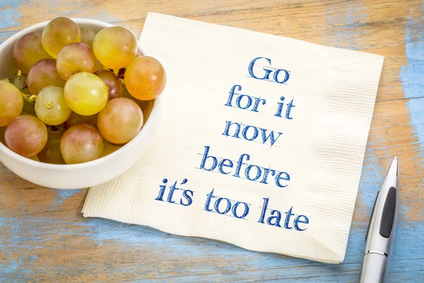 Go for it before it is too late - handwriting on a napkin with fresh grapes