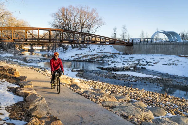 Старший велогонщик едет на велосипеде в зимний закат — стоковое фото