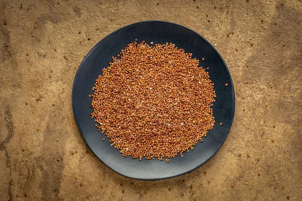 Red quinoa grain on ablack plate — Stock Photo, Image