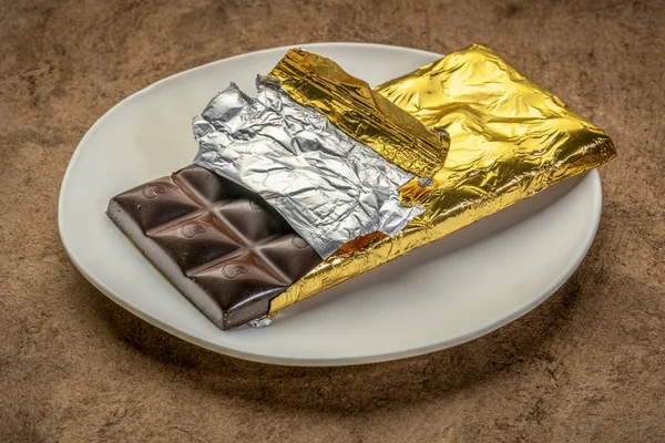 Chocolate bar on plate being unwrapped — Stock Photo, Image