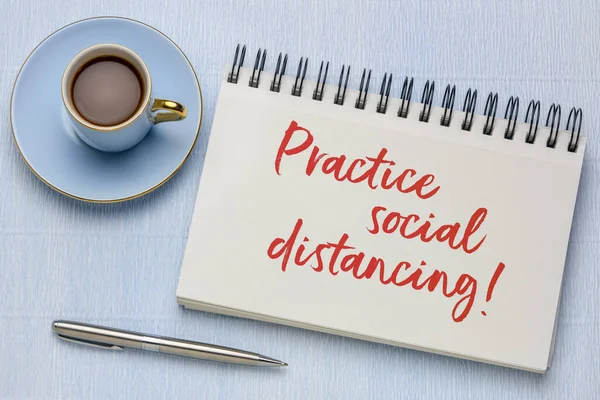 practice social distancing advice or reminder - handwriting in a spiral art sketchbook with a cup of coffee, infection control during covid-19 virus pandemic