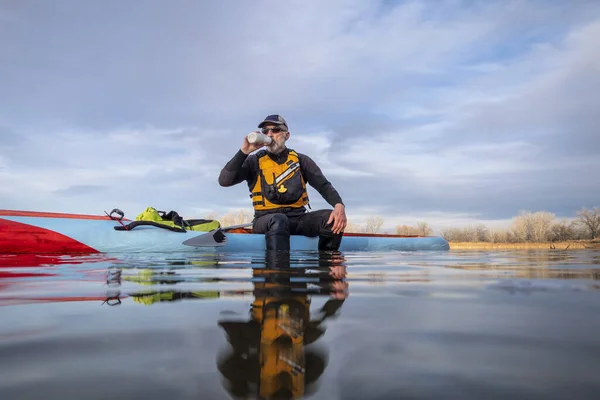 シニア男性パドラーはスタンドアップパドルボード コロラド州の湖 低角度アクションカメラビュー レクリエーション フィットネス トレーニングコンセプトでワークアウト中に水を飲んでいます — ストック写真
