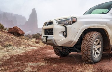 Moab, UT, ABD - 9 Şubat 2020: Toyota 4runner SUV (2016 model arazi aracı) Fisher Towers 'ın arka planında kış koşullarında 4x4' lük bir patikada.