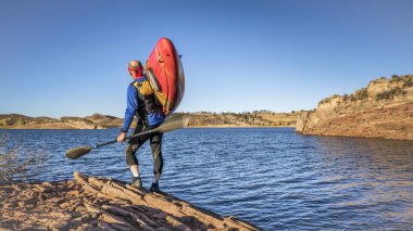 portaging and launching kayak on lake shore, Horsetooth Reservoir, Colorado, recreation concept clipart