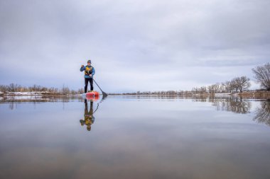 Koronavirüs salgını sırasında sosyalleşme amaçlı kürek çekme. Colorado 'da baharın başlarında kürek çeken yaşlı bir erkek raketçi.