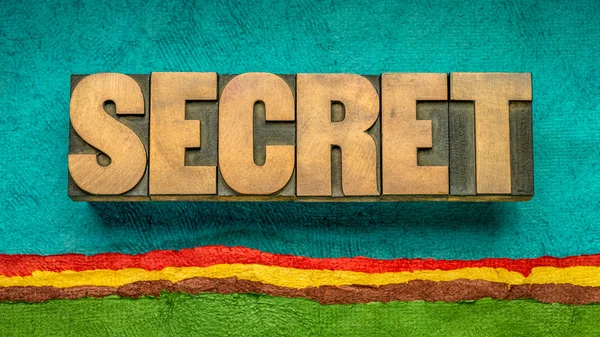 secret word abstract in vintage letterpress wood type against colorful abstract landscape created with textured handmade paper, untold and mystery concept